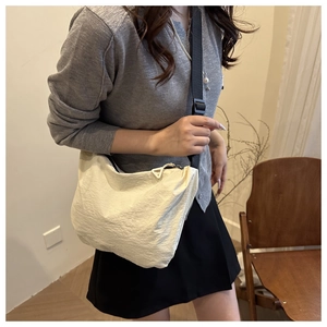 Detail of off-white crossbody bag featuring durable wrinkled fabric and adjustable strap