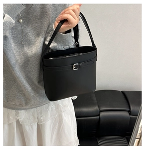 Détail d'un sac seau minimaliste en cuir noir avec boucle argentée et fermeture éclair sécurisée