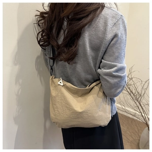 Detail of beige pleated waterproof nylon shoulder bag with unique triangle zipper