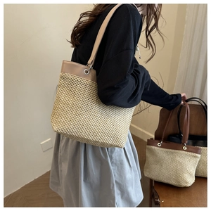 Close-up of handwoven straw tote bags with leather trim and shoulder straps