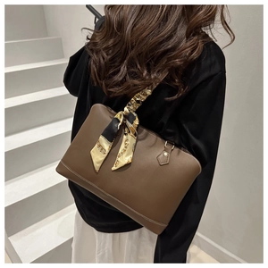 Detailed view of a brown leather tote bag with white stitching and silk scarf accessory