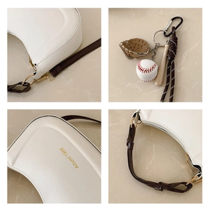 Vue détaillée du sac demi-lune blanc avec charms baseball et texture cuir fine