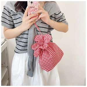 Detail of red and white plaid fabric bucket bag with drawstring closure and floral edge