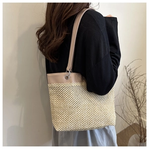Detail of straw tote bag with brown leather strap and metallic silver eyelets