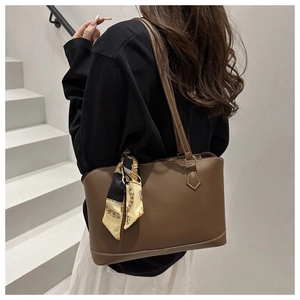 Detailed view of the brown leather tote bag featuring a decorative silk scarf and white stitching