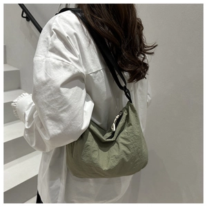 Detail of green dumpling bag showing pleated waterproof fabric and adjustable strap