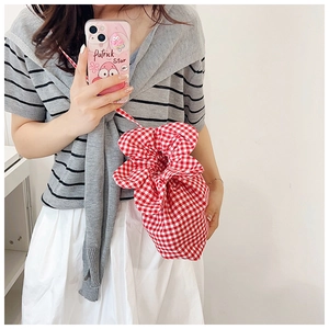 Detail of red and white gingham drawstring bucket bag with floral aesthetic texture