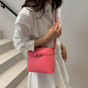 Sac seau rose élégant avec boucle argentée et bandoulière porté par un mannequin