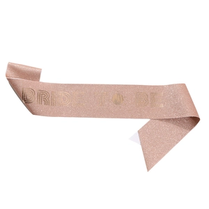 Macro detail of rose gold glitter sash with gold foil BRIDE TO BE lettering for parties