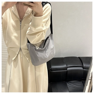 Mirror selfie showing the neutral gray crossbody bag with a white triangle zipper pull