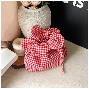 Detail of red gingham drawstring bucket bag with textured cotton fabric and floral pleats