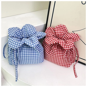 Detail of drawstring bucket bags featuring blue and red gingham patterns and ruffled edges