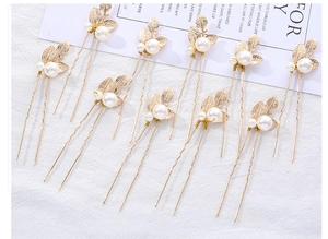 Close-up of 10 gold leaf hair pins featuring white pearls on a minimalist background