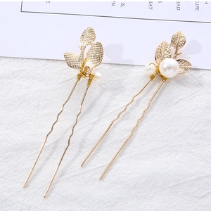 Detail of golden U-shaped hair pins featuring elegant leaf designs and white pearls