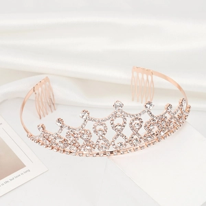 Close-up of rose gold bridal crown with crystal rhinestones and hair combs on silk