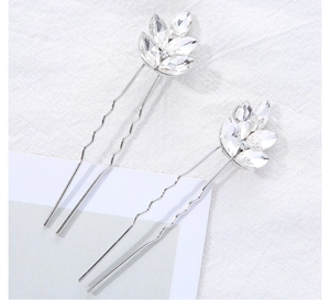 Détail de deux épingles à cheveux en forme de feuille argentée avec strass scintillants
