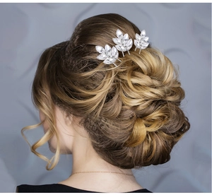Trois épingles à cheveux en cristal argenté en forme de feuilles sur une coiffure de mariée