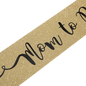 Detail of glitter Mom to be sash with black text for gender reveal party