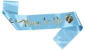Detail der hellblauen Satinschärpe mit goldener Mom to Be Aufschrift und Fußabdrücken
