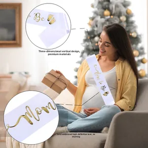 Detail der weißen Satin-Schärpe Mom to Be mit goldener Schrift und Baby-Fußabdrücken