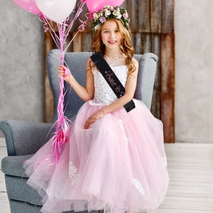 Black satin Sweet 16 birthday sash with pink foil lettering worn by a model in a party setting