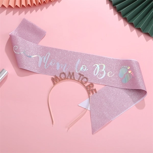 Detail of pink glitter Mom to Be sash and rhinestone headband for baby shower party