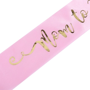 Detail der rosa Satin-Mom-to-Be-Schärpe mit eleganter Goldfolienprägung für Babypartys
