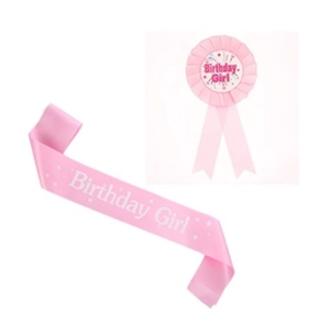 Close-up of pink satin birthday girl sash and matching ribbon badge for party celebrations