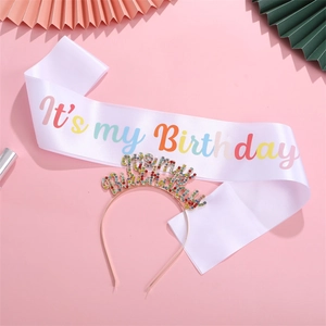 Close-up of birthday party set with rainbow rhinestone headband and satin sash decor