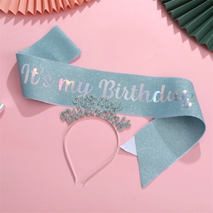 Close-up of light blue glitter birthday sash and matching headband on a pink background