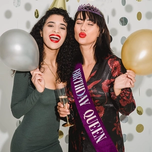 Détail d'une écharpe Birthday Queen en satin violet et d'une couronne en strass sur modèles