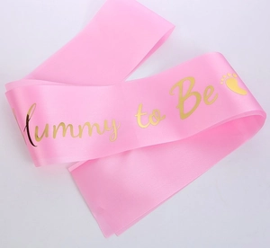 Detailed view of pink satin Mummy to Be sash with gold foil lettering and cute footprints
