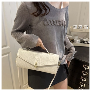 Détail du sac à main blanc crème avec texture tressée et élégant fermoir doré en forme de goutte