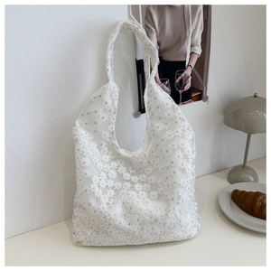 Detail shot of white lace tote bag featuring delicate floral embroidery and sheer texture