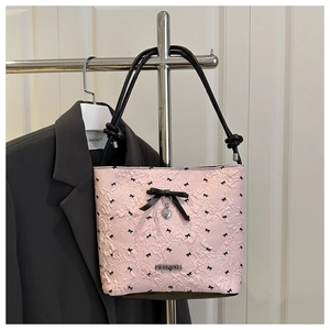Detailed view of pink bucket bag with black ribbon bow and silver heart pendant charm