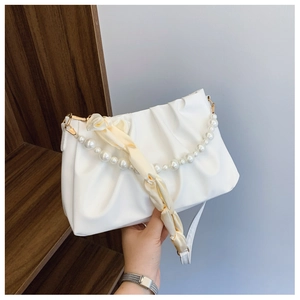Détail du sac plissé blanc avec poignée en perles et accessoire foulard en soie beige