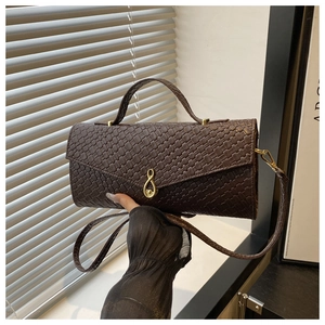 Détail d'un sac à main tressé marron foncé avec fermoir goutte doré et poignée supérieure