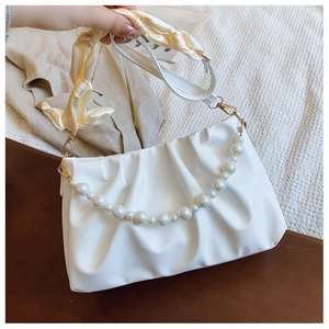 Detail of white pleated cloud bag with pearl chain and silk scarf wrapped handle