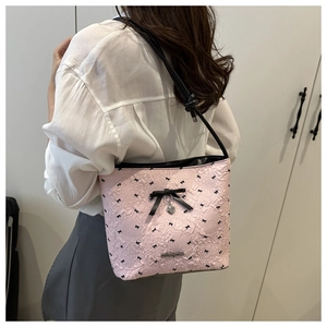 Borsa a secchiello rosa con fiocchi neri e ciondolo a cuore indossata da una modella