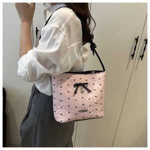 Detail of pink embossed tote bag featuring black bow patterns and a silver heart pendant