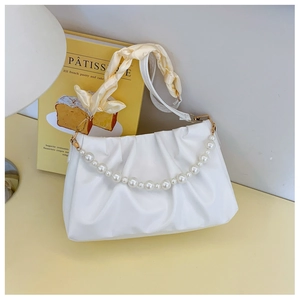 Detail of white pleated cloud bag with pearl handle and yellow silk scarf wrapped strap