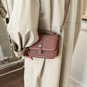 Minimalist woven texture crossbody bag in brown leather shown on model with beige coat