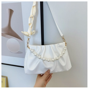 Detail of white pleated cloud bag featuring large pearls and a yellow silk bow detail