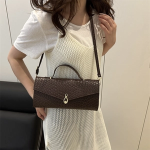 Sac bandoulière marron foncé avec texture tissée et fermoir infini doré porté