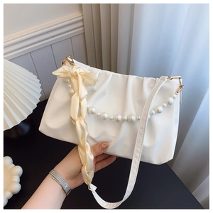 Detail view of white ruched cloud bag featuring pearl handle and cream silk bow accent
