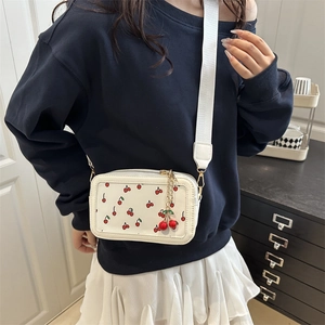 Borsa tote bianca con stampa a ciliegie, tracolla larga e ciondolo 3D su modella