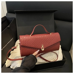 Détail du sac en cuir tressé bordeaux avec boucle dorée en forme d'infini dans son coffret