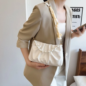 White pleated cloud bag featuring a large pearl chain and a wide beige fabric strap
