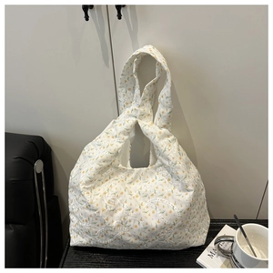 Detail view of white canvas shoulder bag with yellow floral print and paisley embroidery