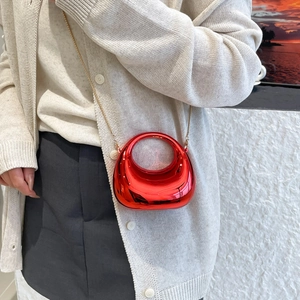 Glossy red moon shaped mini handbag with gold chain strap shown on model's hand